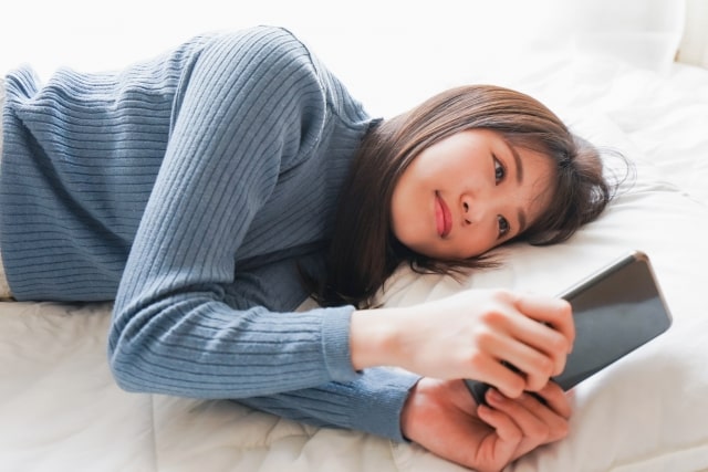 ベッドでスマホ操作する女性